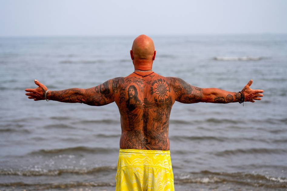 A confident bald man smiling with a healthy, shiny scalp against a clean background