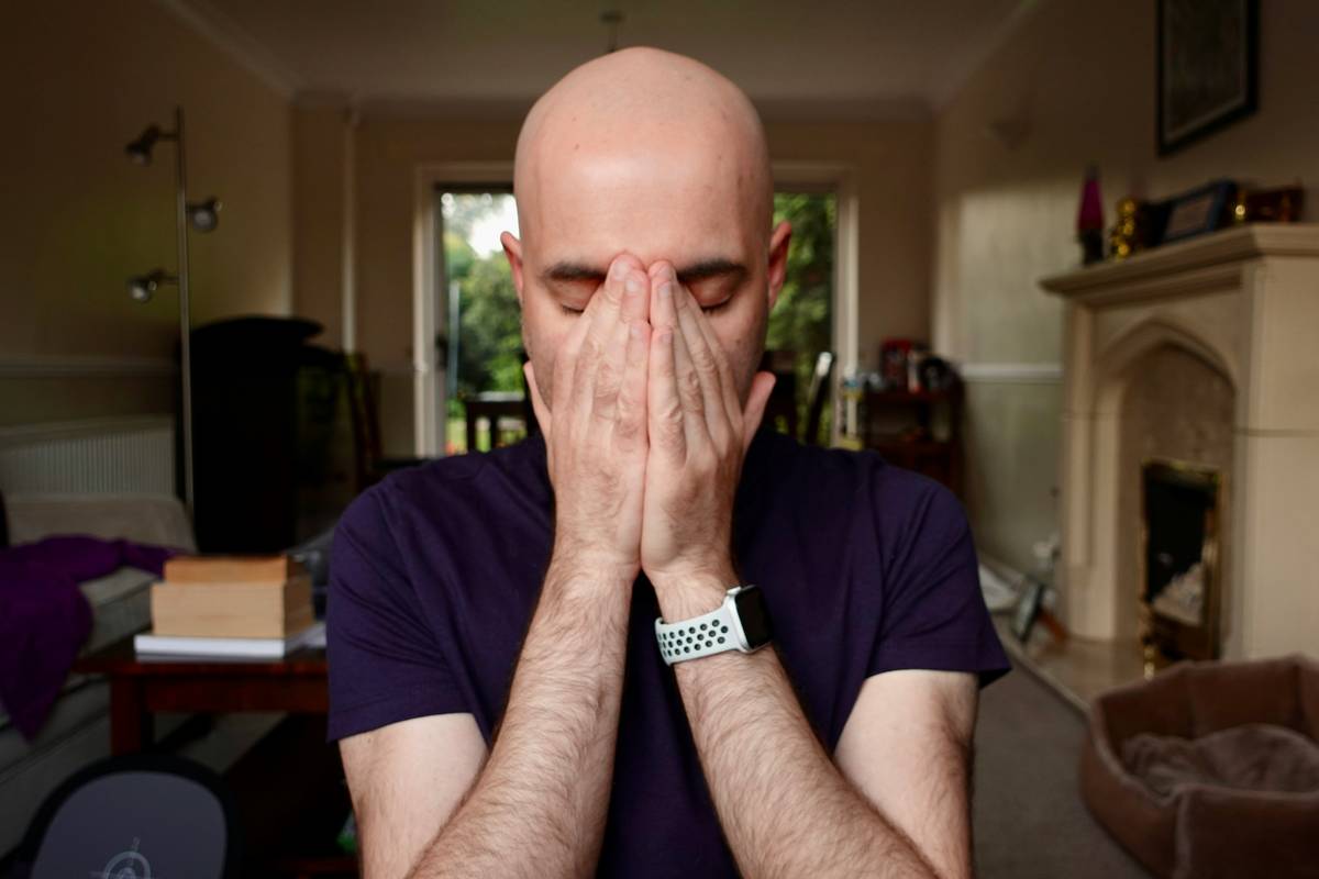 Man applying sunscreen while taking care of a bald head outdoors