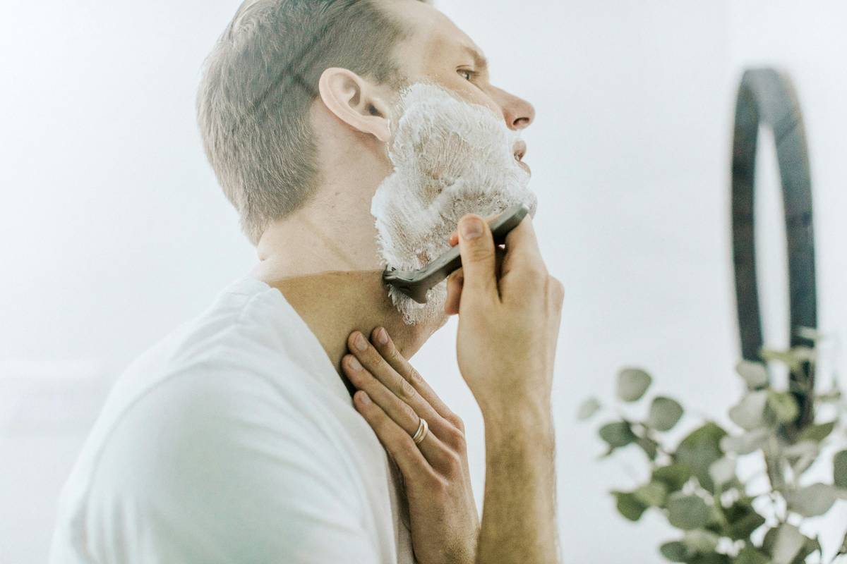 how to shave your head bald: close-up of someone using a safety razor on a clean, wet scalp with pre-shave oil